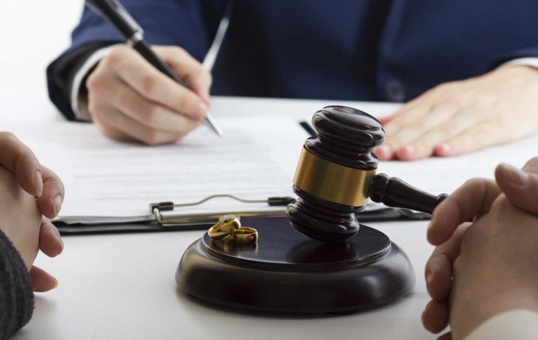 A judge's gavel rests beside a wedding ring, symbolizing the legal proceedings of divorce.