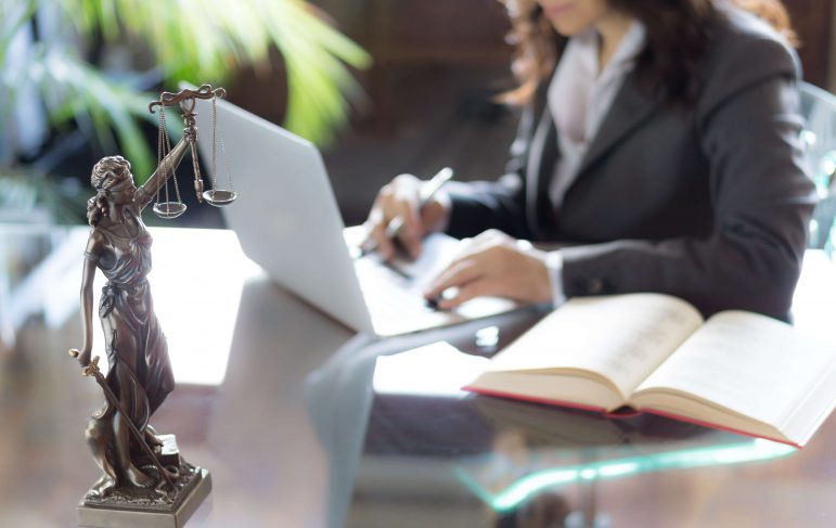 A professional woman in a suit seated at a desk, focused on her laptop, exemplifying a modern work environment.