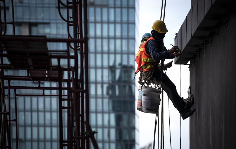 Construction worker wearing safety harness and safety line working at high place