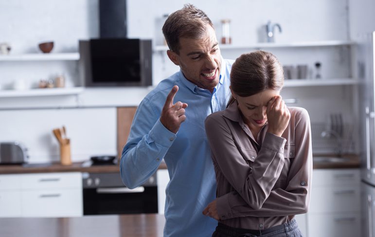 aggressive man in shirt screaming at crying wife during quarrel