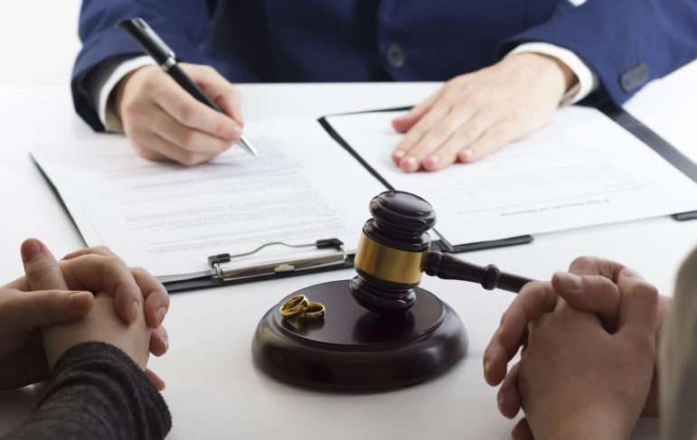 A wedding ring lies next to a judge's gavel, representing the intersection of love and legal dissolution in divorce.