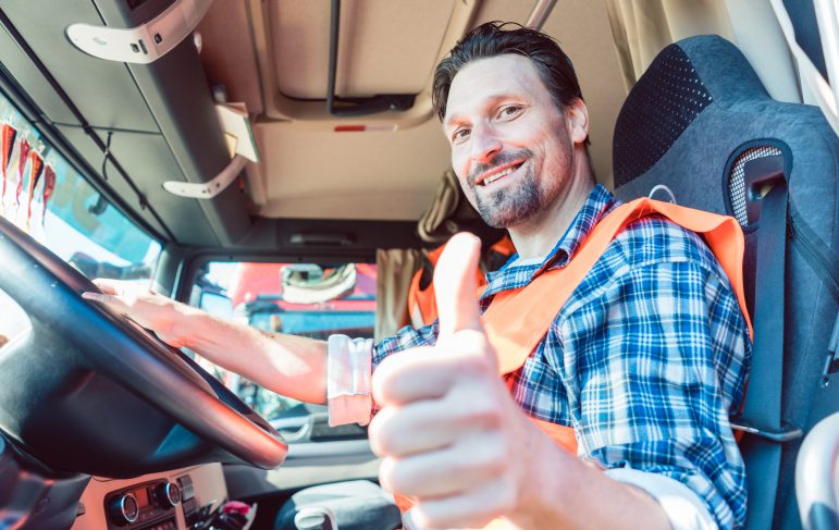 Truck driver man sitting in cabin giving thumbs-up